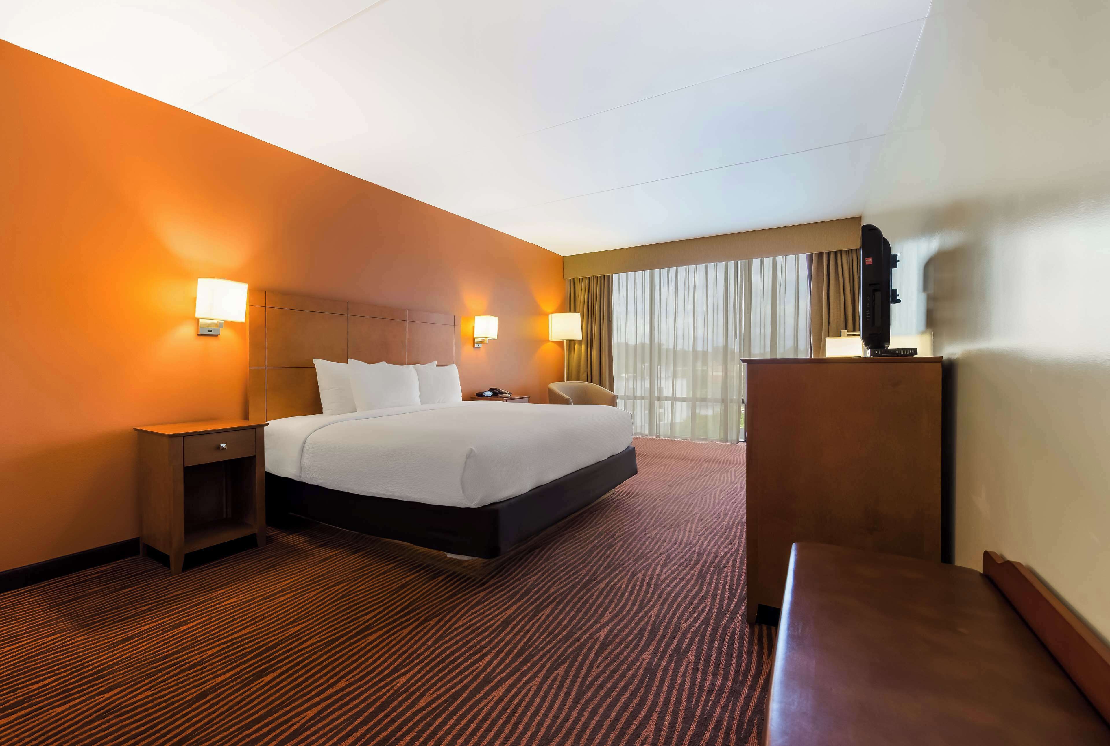 Una habitación de hotel con una cama grande, un escritorio y una silla.