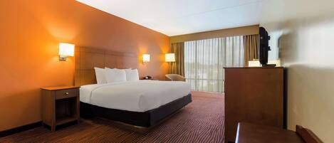 A hotel room with a large bed, a desk, and a chair.