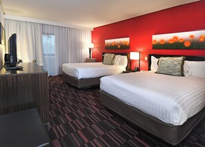 A hotel room with two beds, a desk, a TV, and a red accent wall. - Holiday Inn Irving Las Colinas by IHG (Irving)