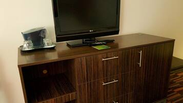 A flat-screen TV on a wooden cabinet with drawers and a tray with glasses.