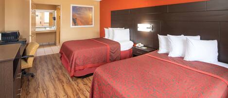 A hotel room with two beds, a desk, a chair, and a bathroom visible through an open door.