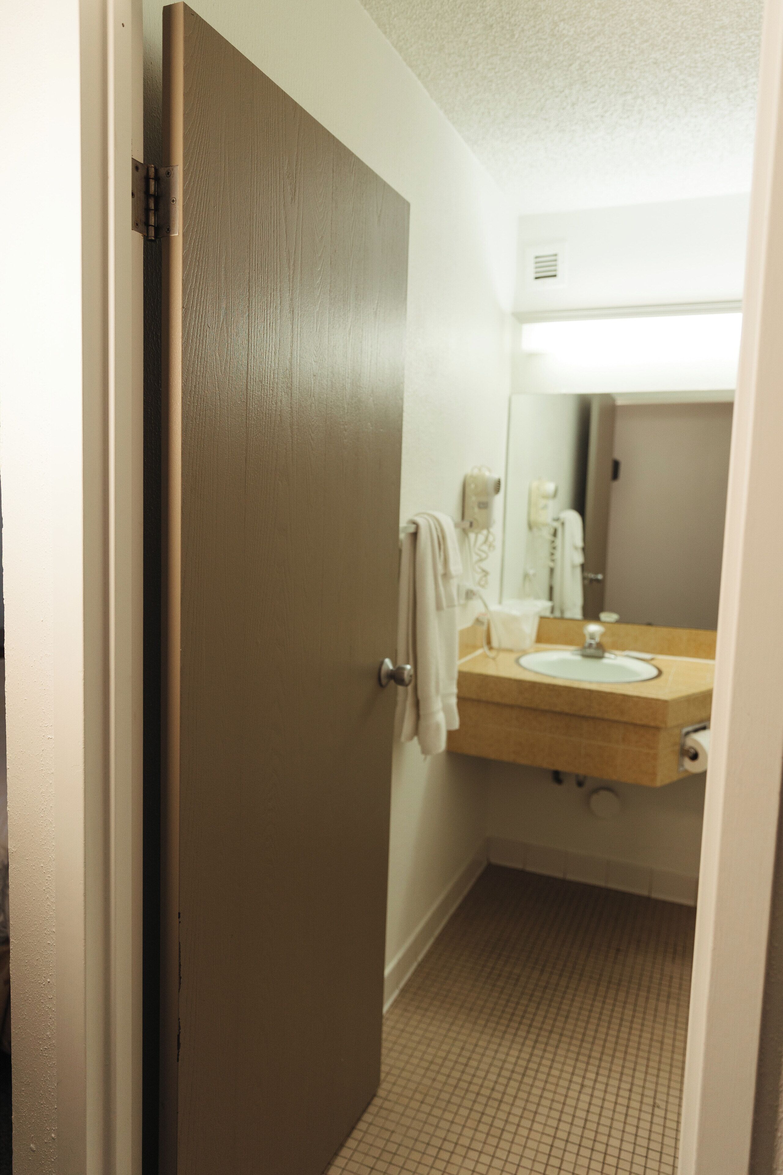A bathroom with a wooden door, a sink, and a mirror.