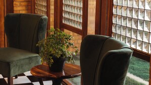 Una habitación con dos sillones tapizados en verde, una mesita de madera con una planta en maceta y un suelo a cuadros.
