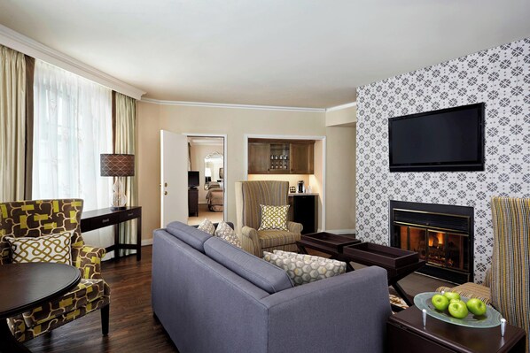 A living room with a sofa, armchairs, a TV, and a fireplace.