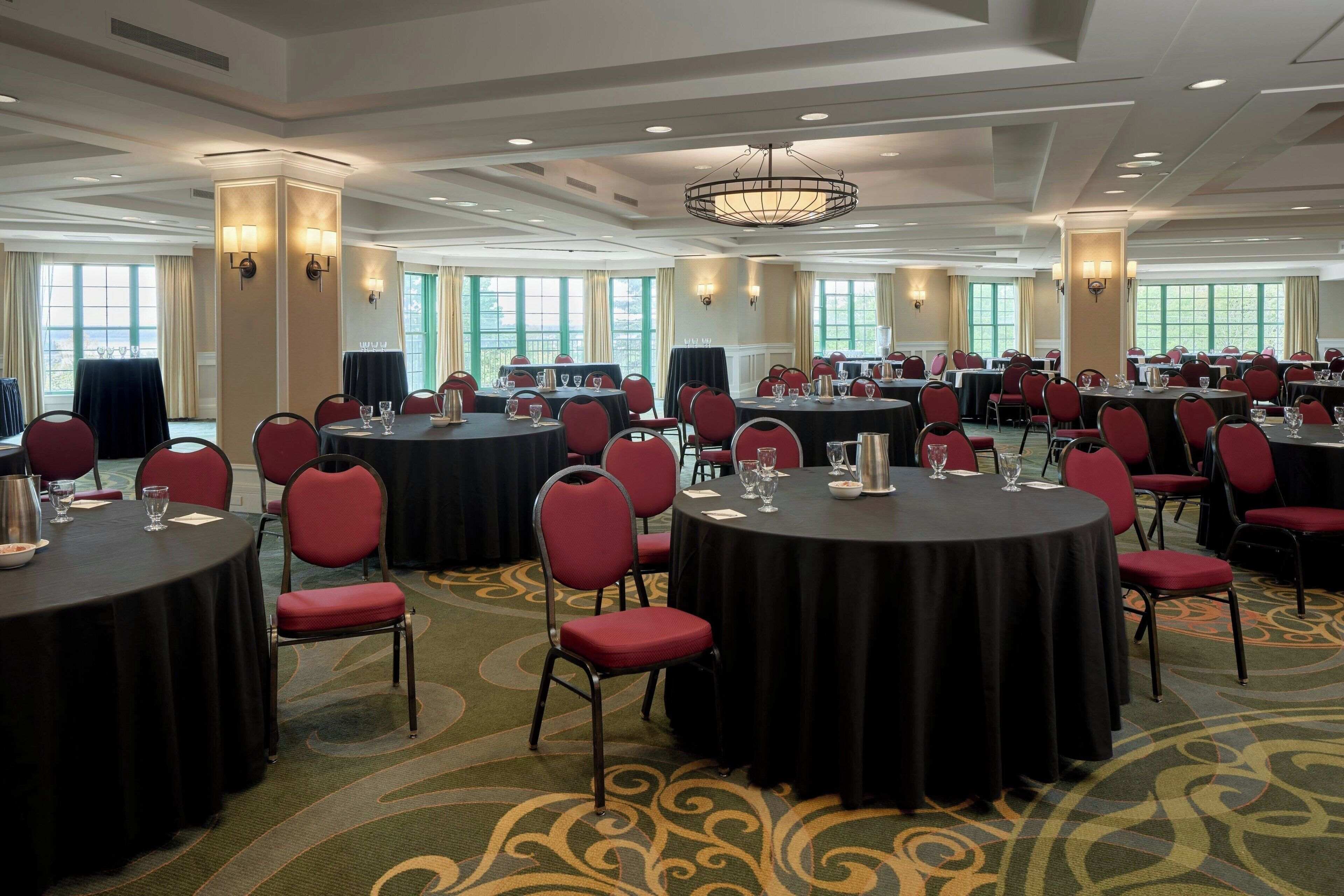A conference room with round tables, red chairs, and a carpeted floor.