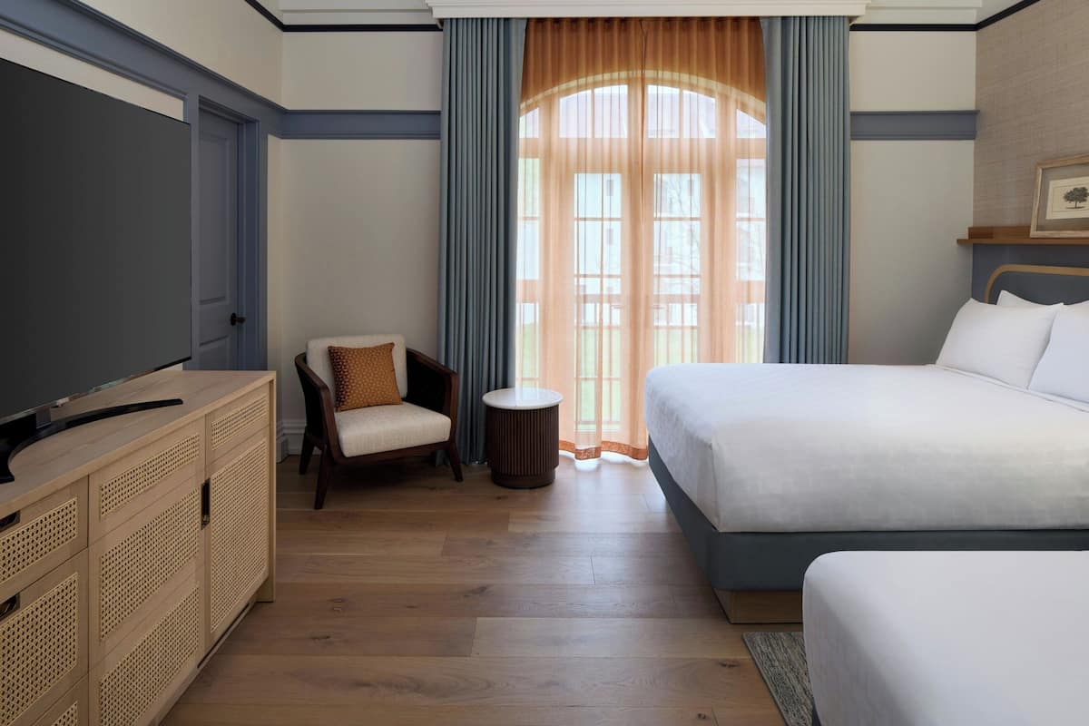 Une chambre d’hôtel avec un lit, une chaise, un téléviseur et une armoire en bois.