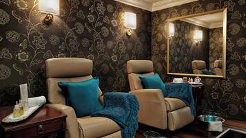 Relax in comfort with two plush chairs and a side table, surrounded by elegant decor and a large mirror.