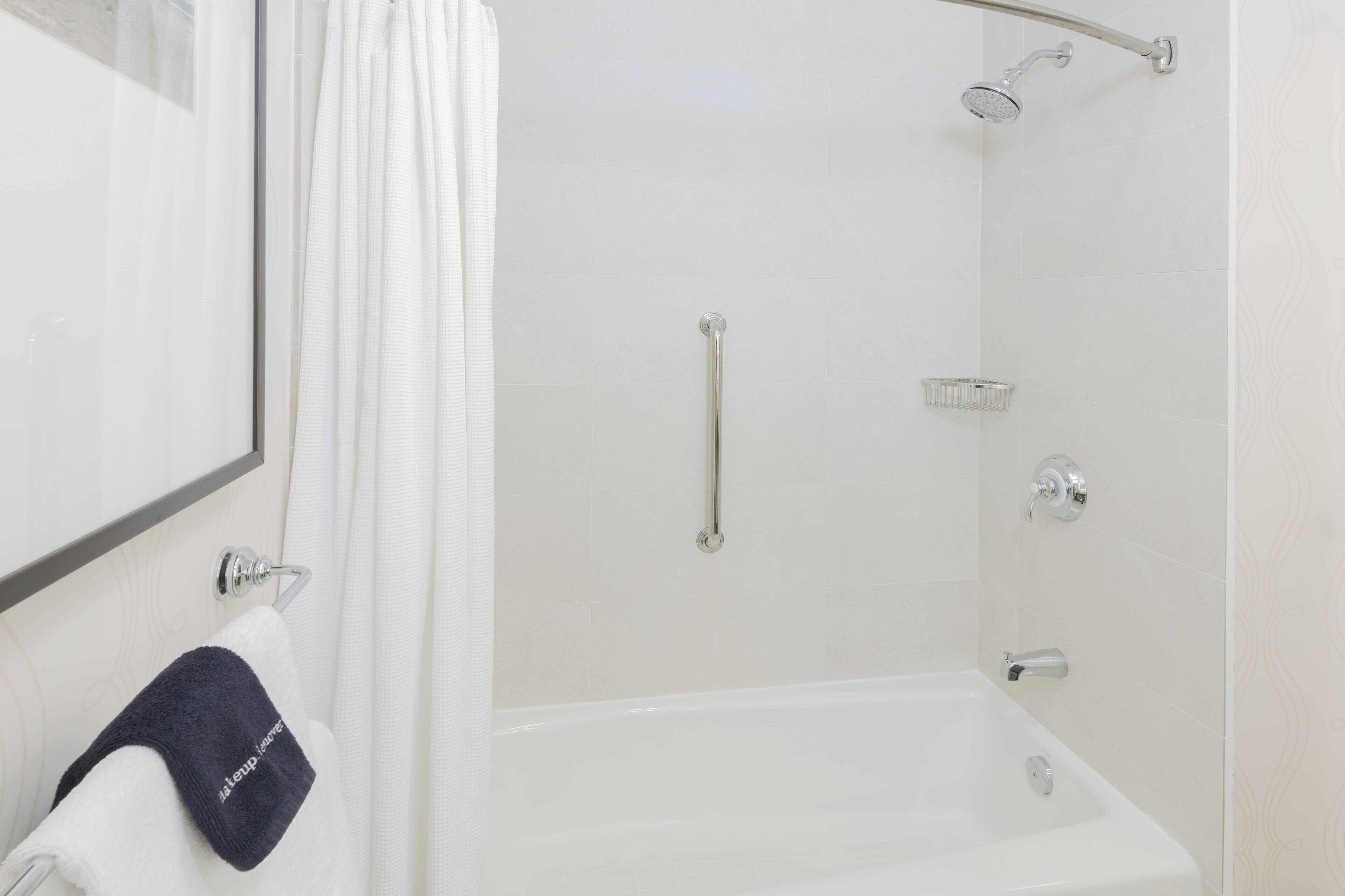 A modern bathroom with a bathtub, a shower, and a handrail.