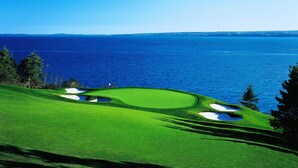 Campo de golf con búnkeres y vista al océano.