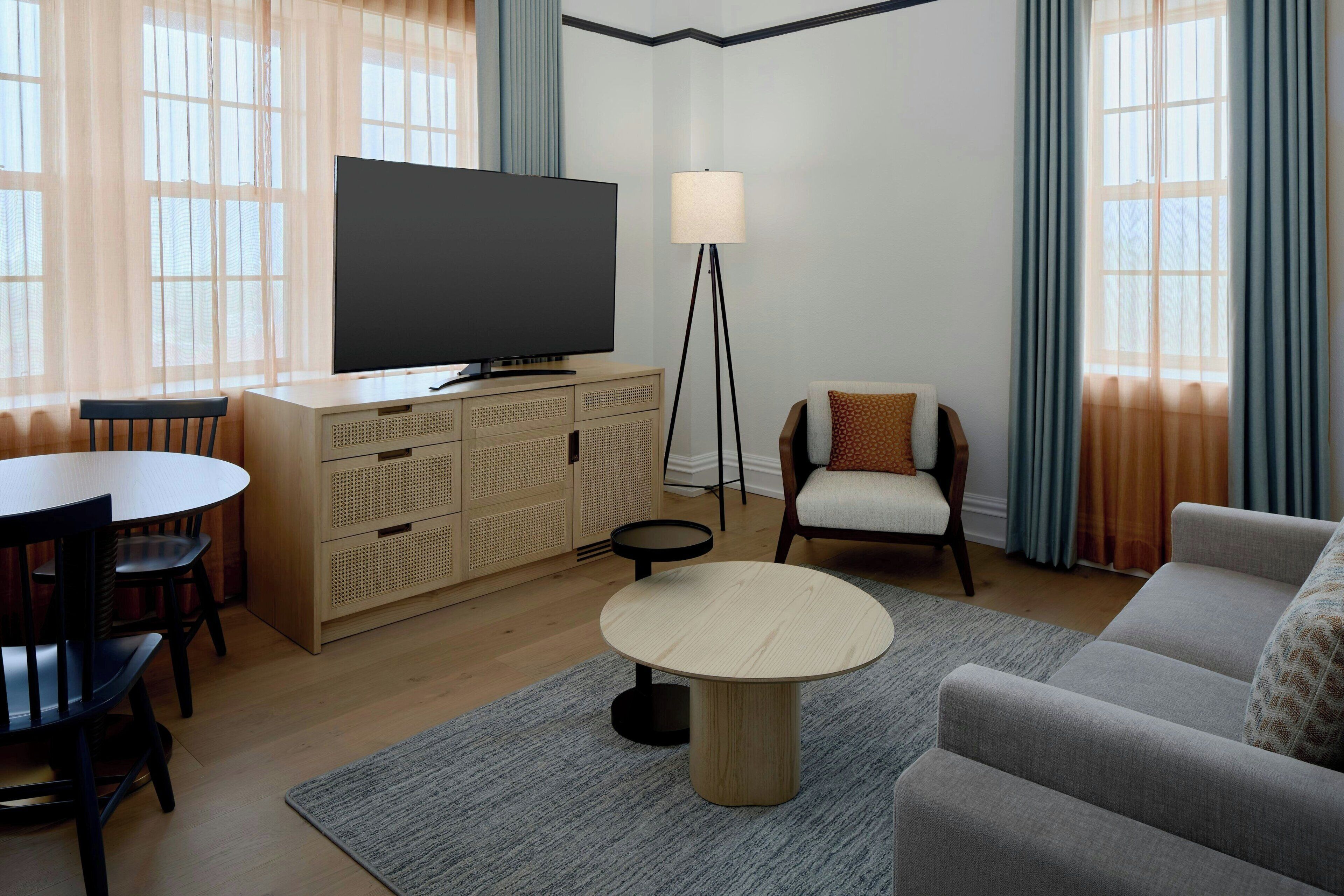 A living room with a television, a sofa, a dining table, and a lamp.