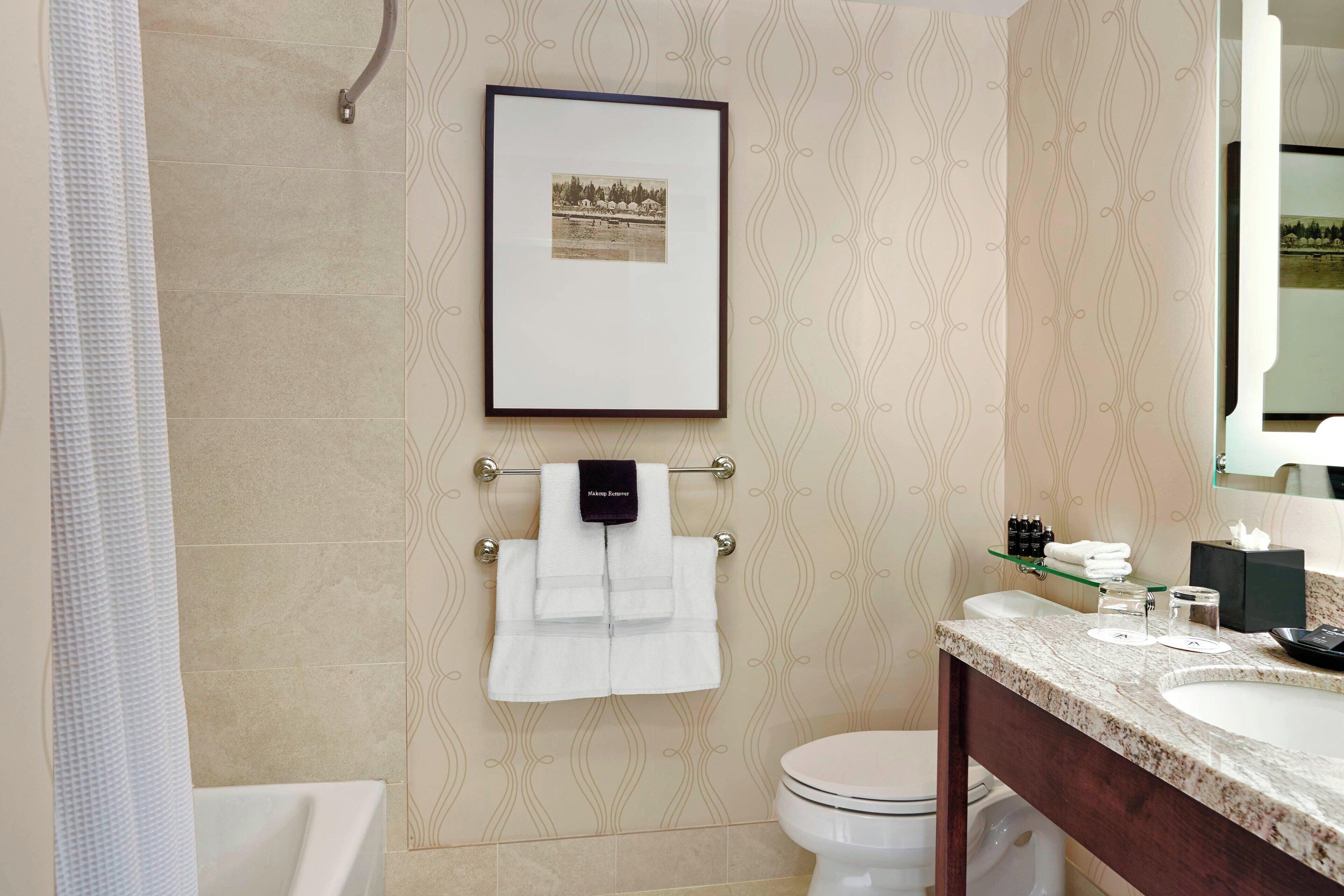 A bathroom with a bathtub, toilet, sink, and a framed picture on the wall.