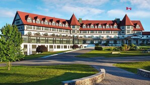 Un hotel grande y moderno con fachada simétrica, varios techos rojos y una destacada bandera canadiense.