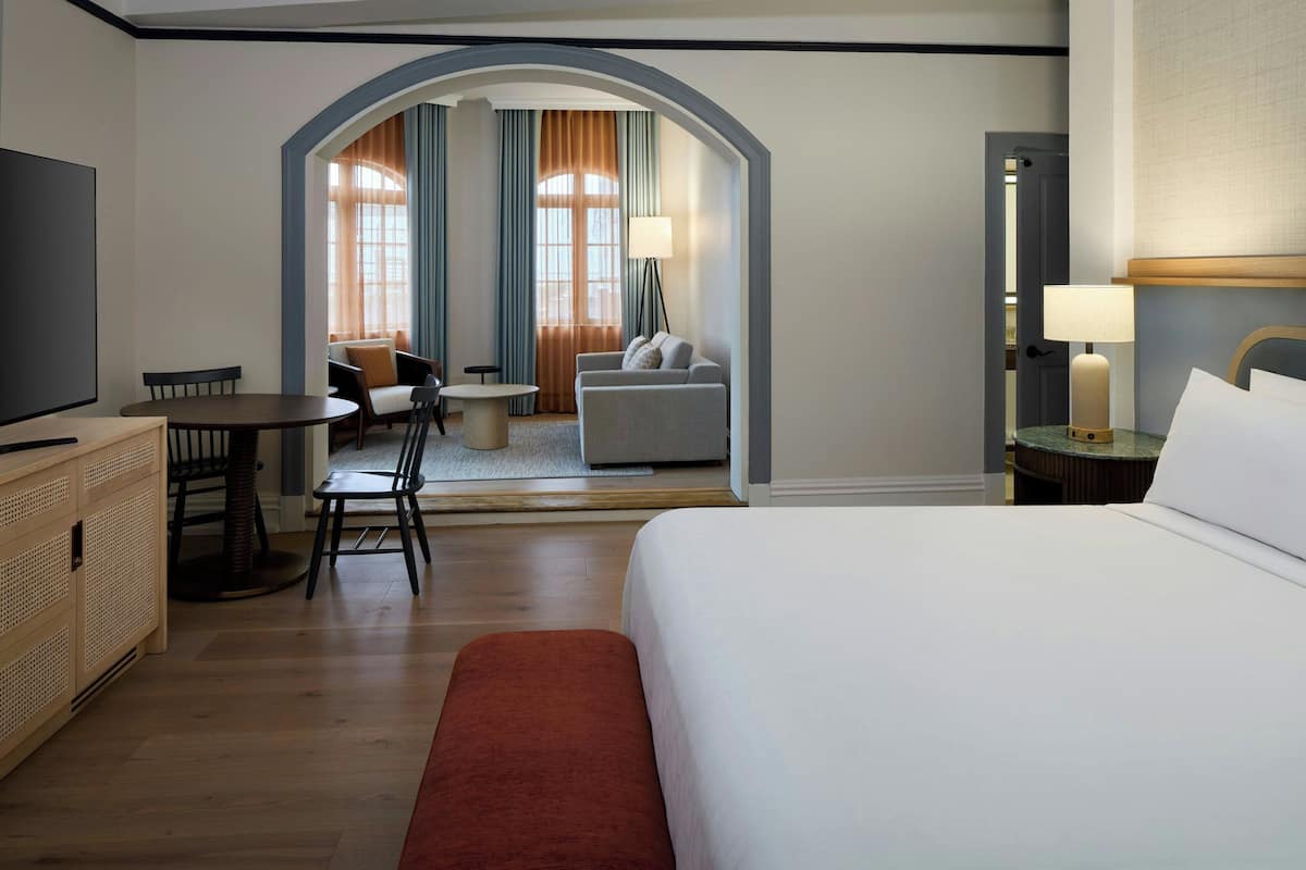 Une chambre d’hôtel comprenant un lit, une télévision, un bureau avec des chaises, un canapé et une lampe.