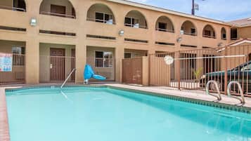 Un espace piscine agrémenté d’un panneau indiquant « Rodeway Inn », une piscine clôturée et un espace détente abrité.