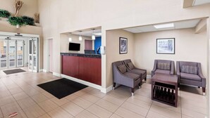 A spacious lobby with a reception desk, seating area, and a view of the outside.