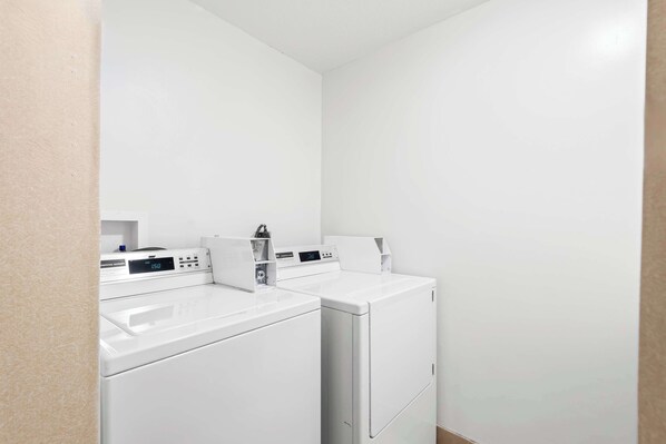 A laundry area with two white washing machines and a control panel.