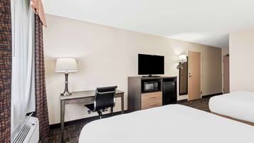 Une chambre d’hôtel avec un lit, un bureau avec un ordinateur, une télévision, une lampe et une porte.