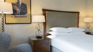 A hotel room with a large bed, two bedside tables with lamps, a chair, and a framed picture on the wall.
