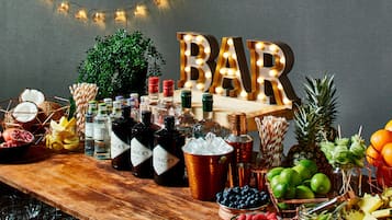 Disposição de bar com garrafas, frutas e uma placa com a inscrição 'BAR'.