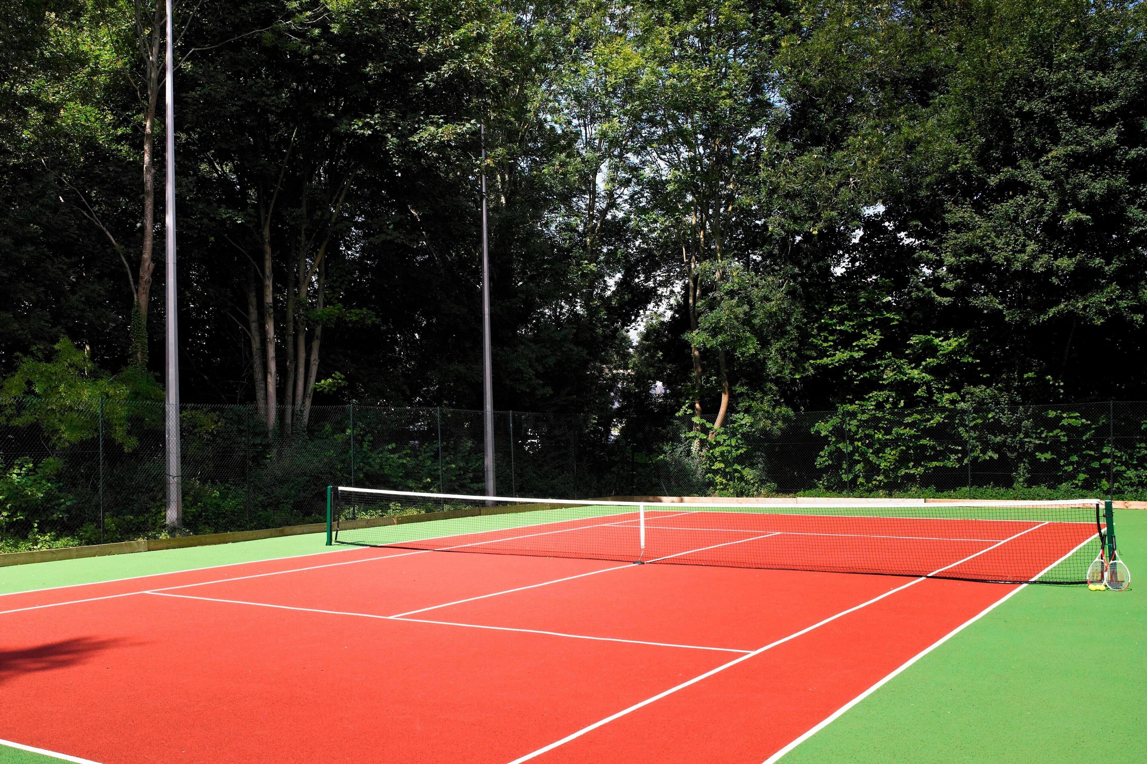 Ein Tennisplatz mit Netz, umgeben von Bäumen.