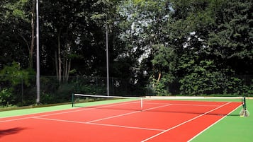 Ein Tennisplatz mit Netz, umgeben von Bäumen.