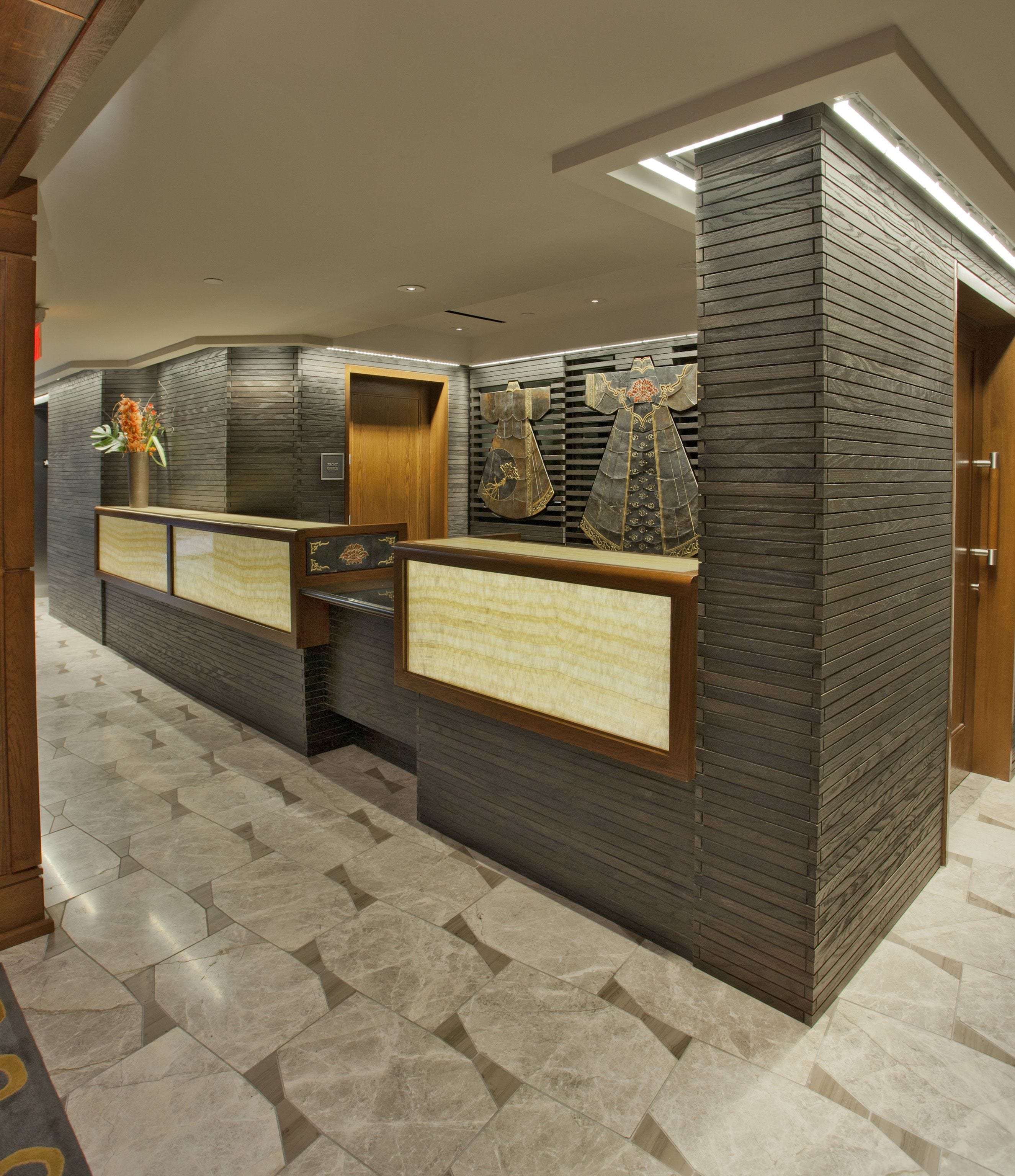A reception area with a modern design, featuring a reception desk, a wall-mounted display, and a patterned floor.