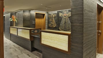 A reception area with a modern design, featuring a reception desk, a wall-mounted display, and a patterned floor.