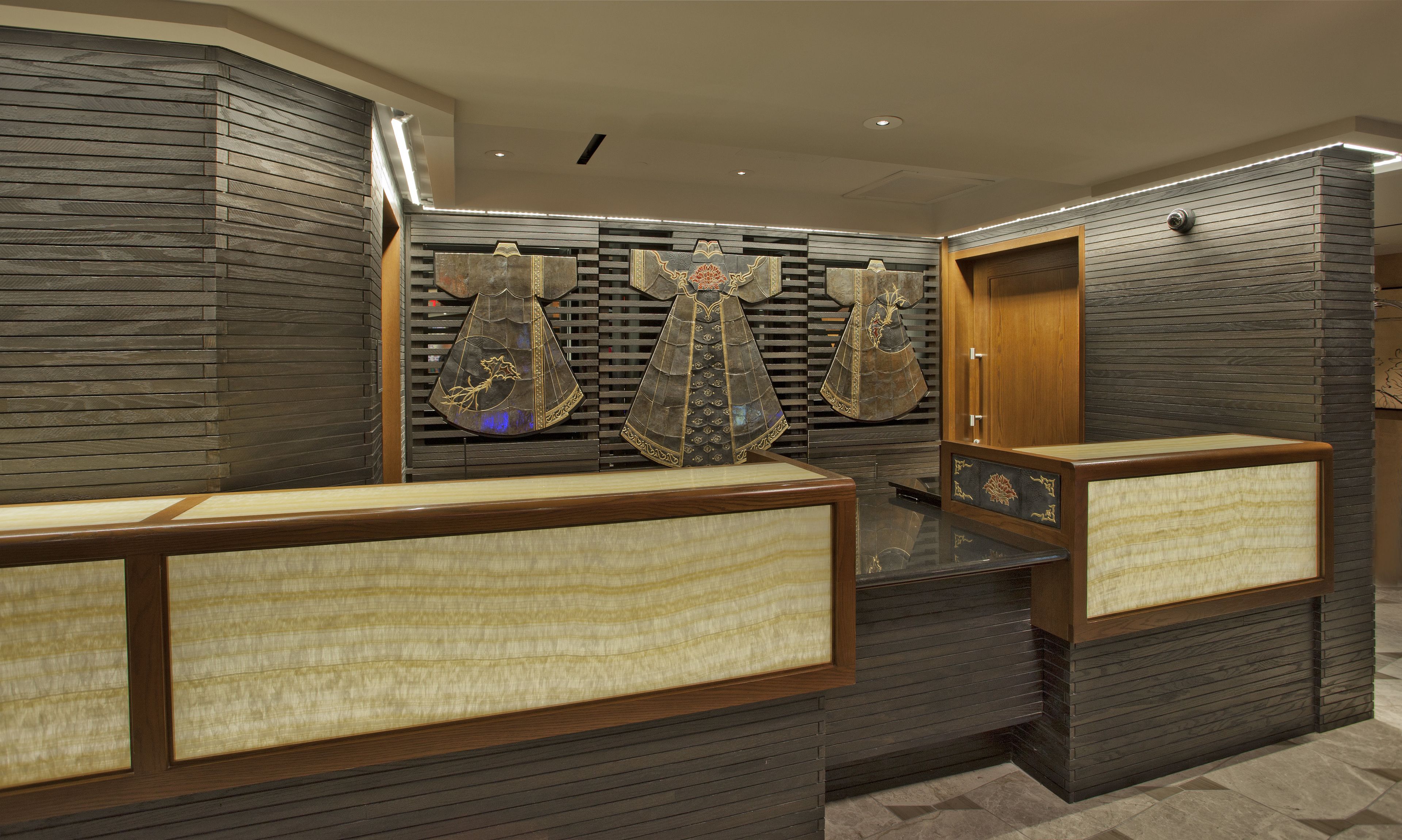 A reception area with a modern design, featuring a reception desk, a wooden door, and decorative wall panels.