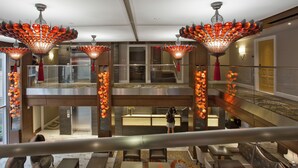 Un hall d’hôtel au design moderne, comprenant un espace salon spacieux, un comptoir d’accueil et un escalier doté d’une rampe en verre.
