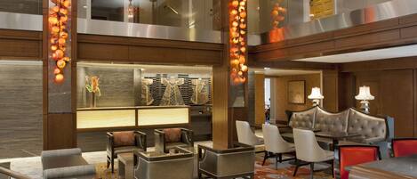 A spacious lobby with a high ceiling, modern furniture, and decorative lighting fixtures.