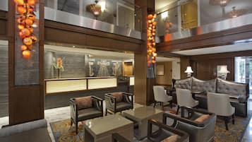 A spacious lobby with a seating area, a reception desk, and a view of the upper floor.