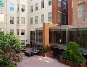 A multi-story building with a courtyard featuring outdoor seating and greenery.