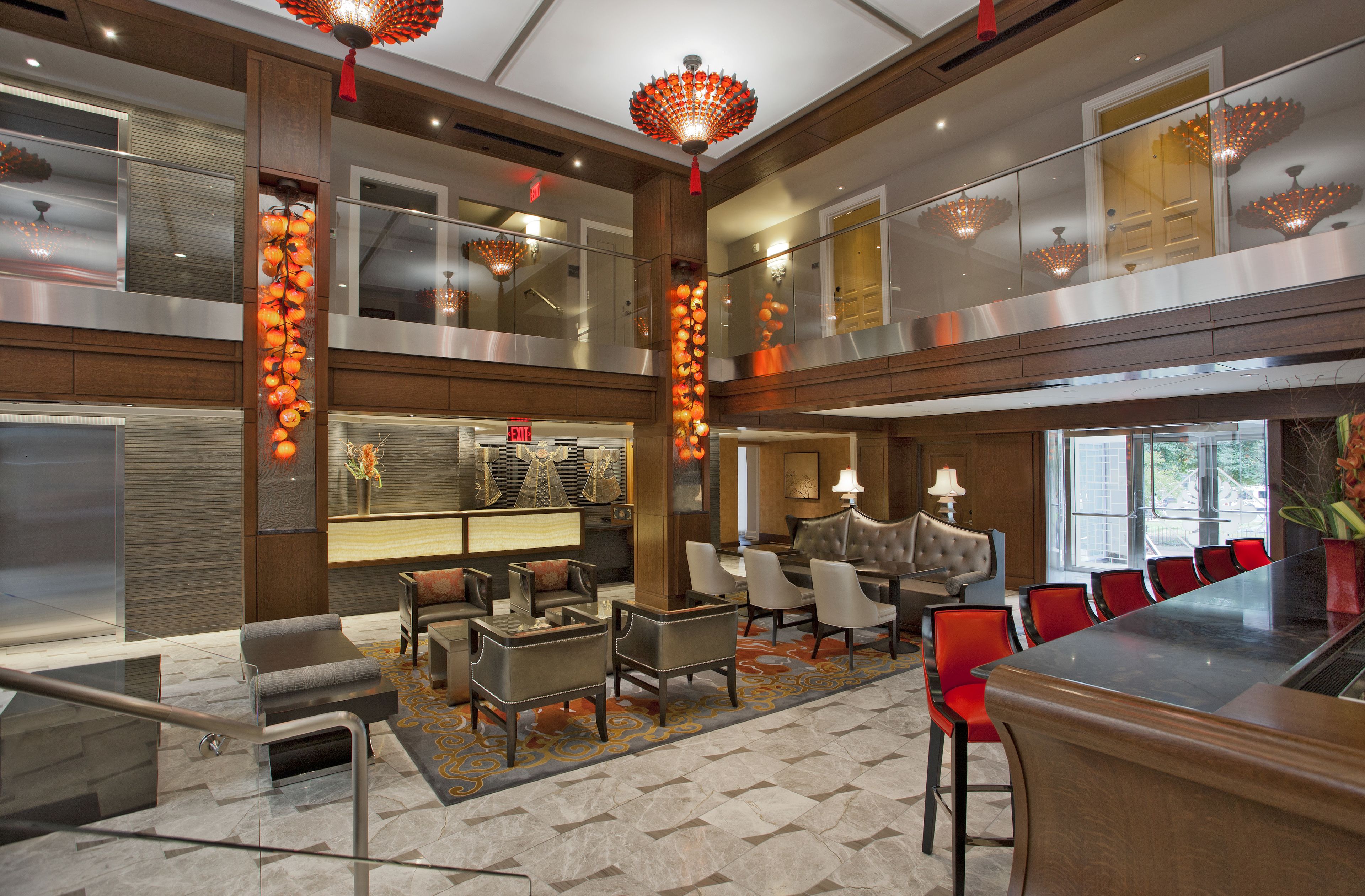A spacious lobby with a high ceiling, modern furniture, and a central bar area.