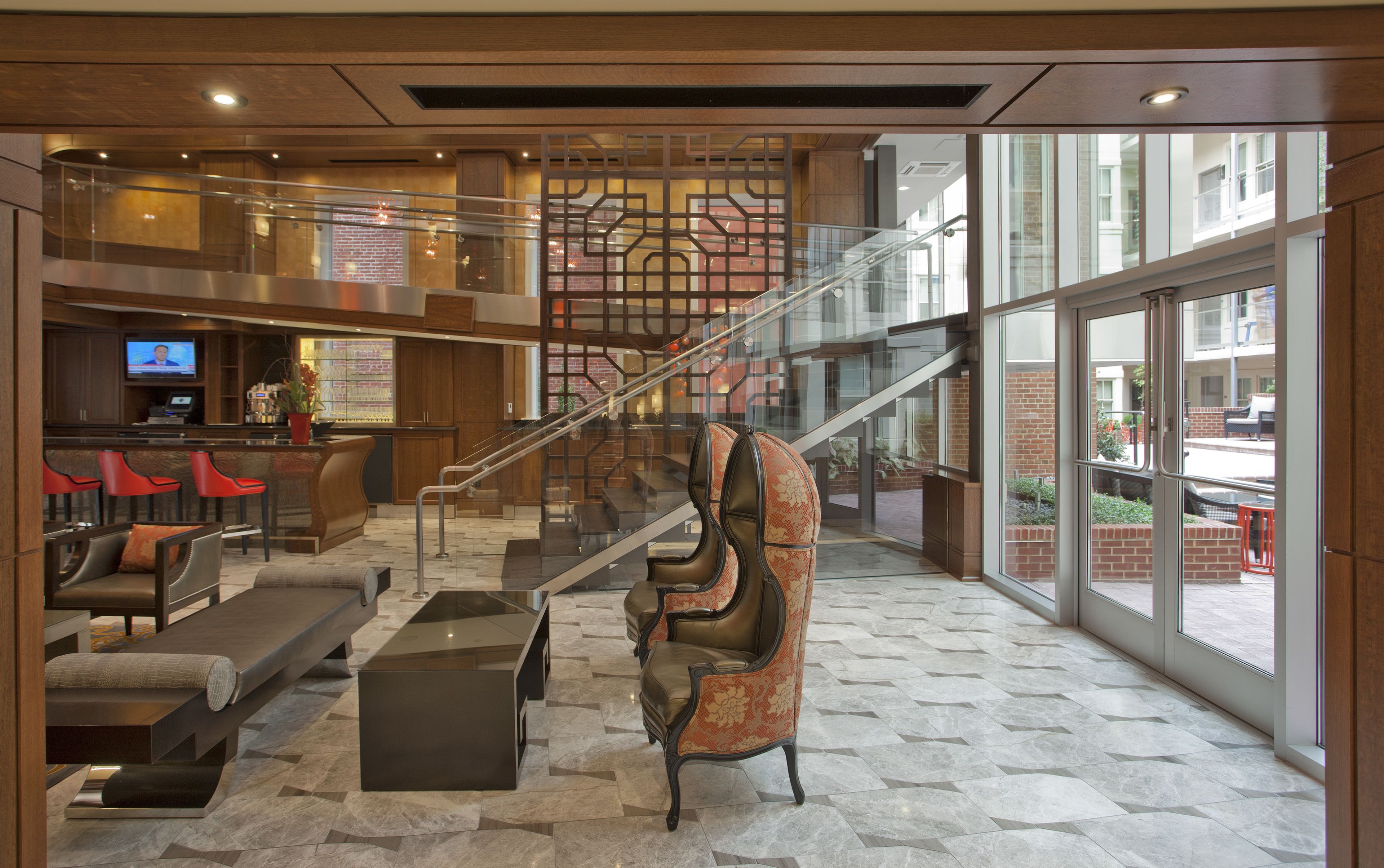 A lobby with a staircase, seating area, and a TV screen.