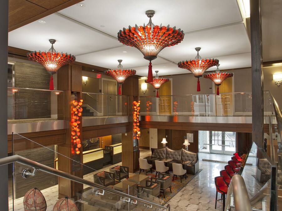 A spacious lobby with a staircase, modern lighting fixtures, and seating areas.