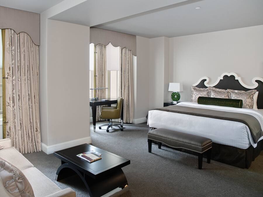 Una habitación de hotel con una cama, un escritorio, una silla y un sofá.