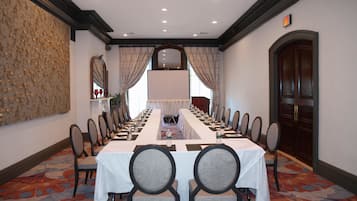 A conference room with a long table, chairs, and a projector screen.