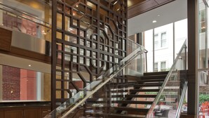 Un escalier moderne avec des rampes en verre et un luminaire décoratif au plafond.