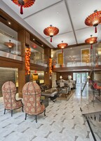 A spacious lobby with high ceilings, ornate chandeliers, and a grand staircase.