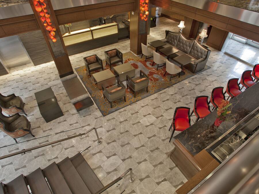 A modern lobby with a reception desk, seating area, and a staircase.