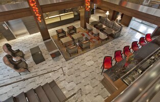 A modern lobby with a reception desk, seating area, and a staircase.