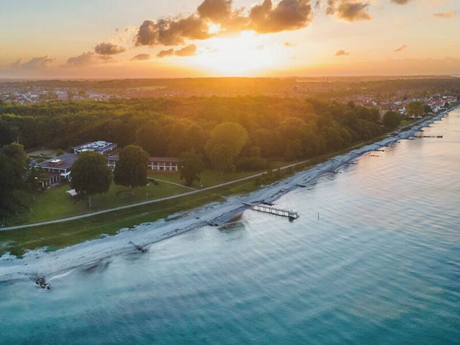 An aerial view of a coastal area with a bridge, a park, and a building complex.