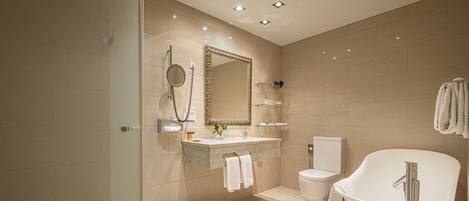 A modern bathroom with a freestanding bathtub, a glass shower enclosure, a vanity with a mirror, and a toilet.