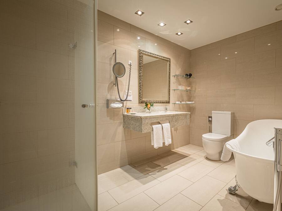 A modern bathroom with a freestanding bathtub, a glass shower enclosure, a vanity with a mirror, and a toilet.