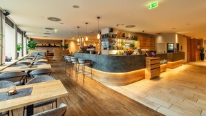 Un moderno vestíbulo de hotel con una recepción, zona de bar y asientos para huéspedes.
