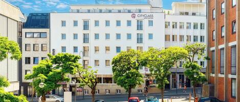 Un Hotel CityClass con fachada moderna, varios pisos y un estacionamiento con varios coches.