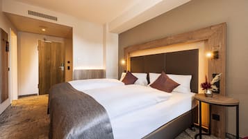 Ein Hotelzimmer mit einem großen Bett, einem Holz-Kopfteil, einem Nachttisch mit einer Vase und einem Teppichboden.