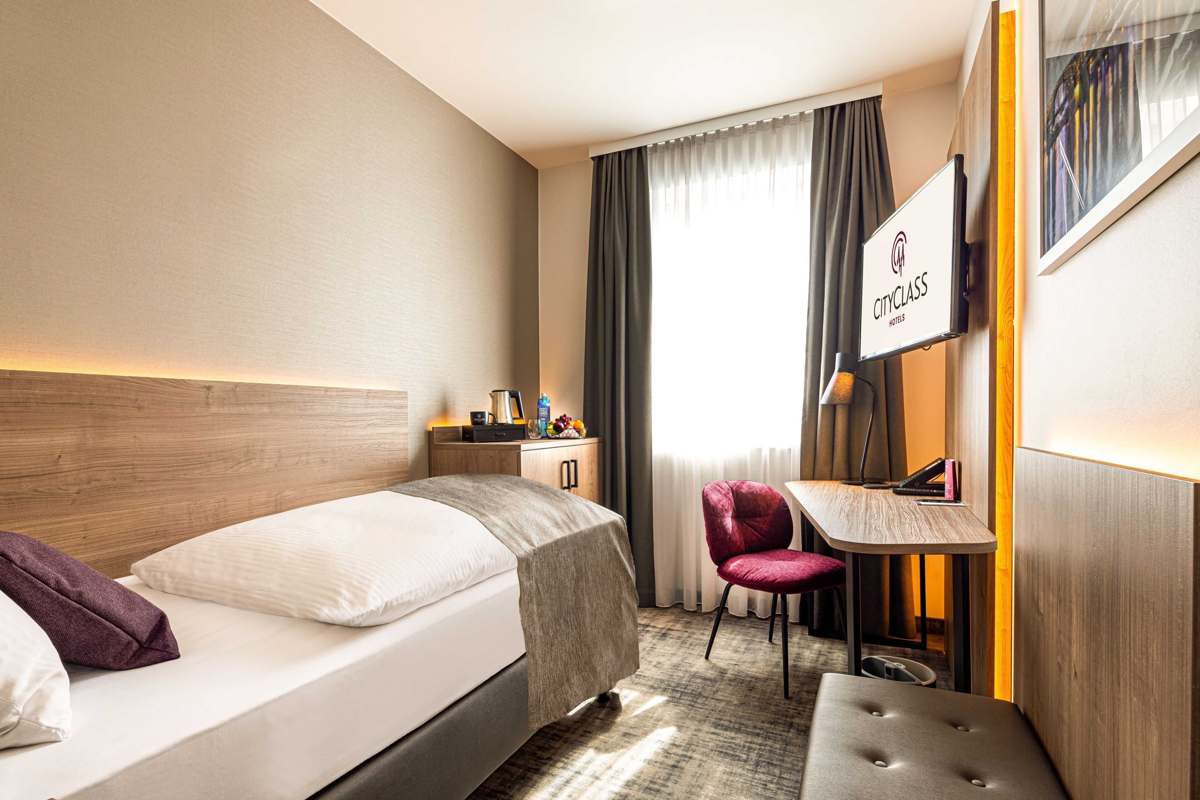 A hotel room with a bed, a desk, a chair, and a mirror.