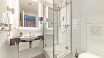 Ein modernes Badezimmer mit einer Duschkabine, einem Waschbecken mit Marmorplatte und einer Toilette.