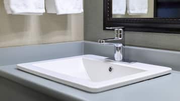 A bathroom with a white sink, chrome faucet, and a mirror above it.